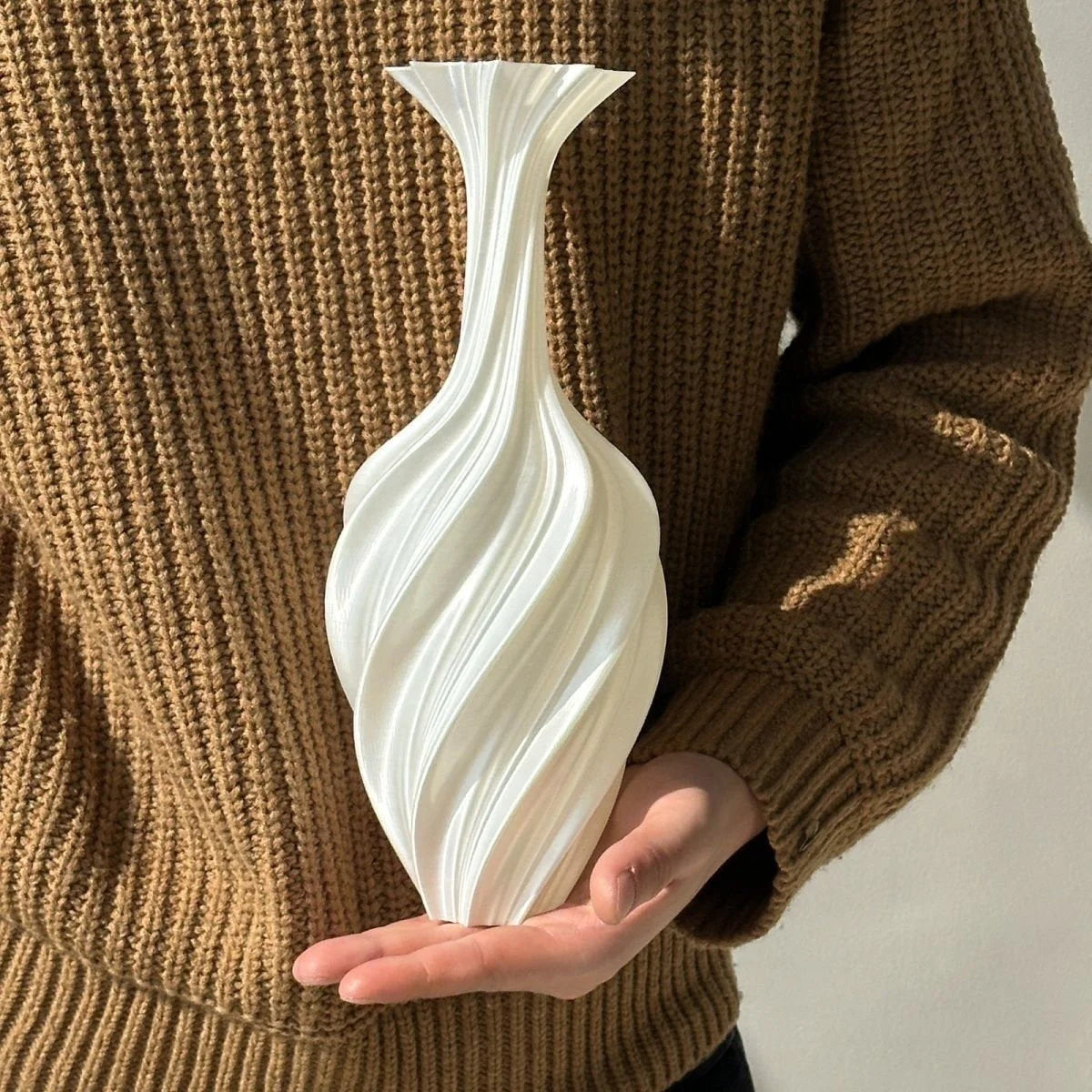 A person holding the Pearl White Sculptural Swirl Vase, showing its size and texture - RoomDen