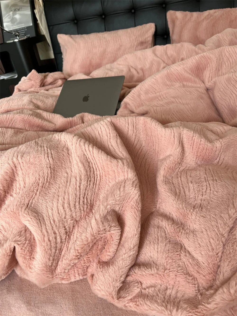 Close-up of a plush, ruched Blush Pink flannel fleece duvet cover with a laptop resting on it. - RoomDen