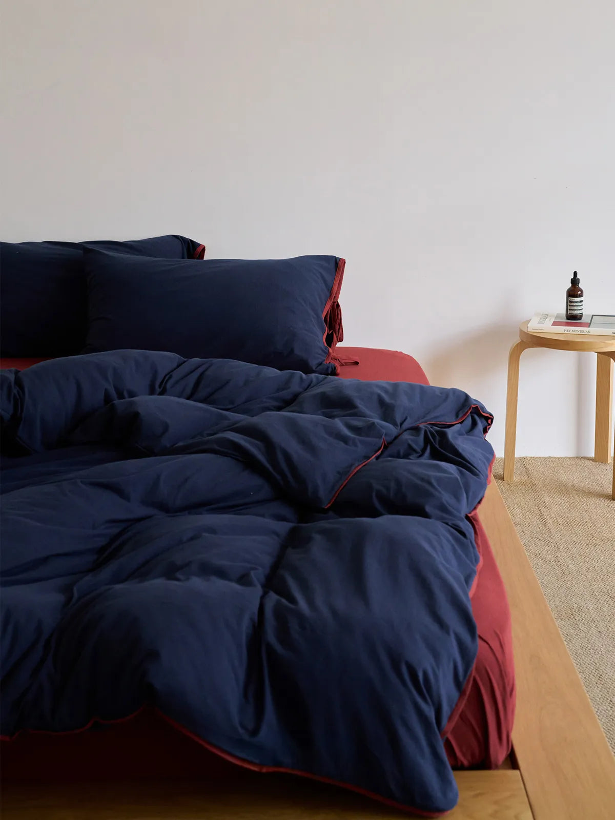Lifestyle image of the Navy & Terracotta bedding set in a modern bedroom with a wooden side table. - RoomDen