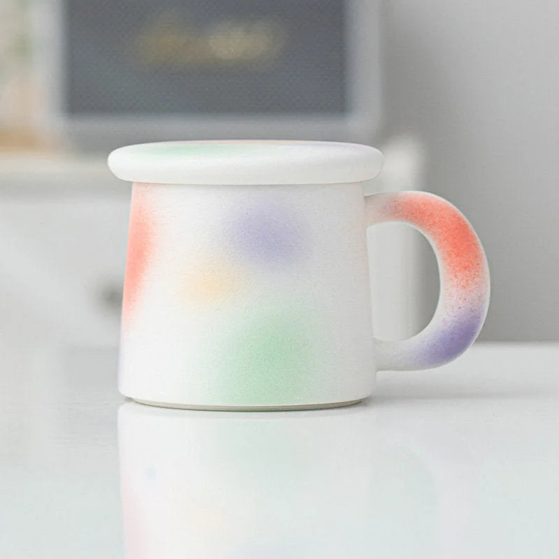 Side view of the Pastel Sprinkle Frosted Ceramic Mug with lid on a white surface - RoomDen.
