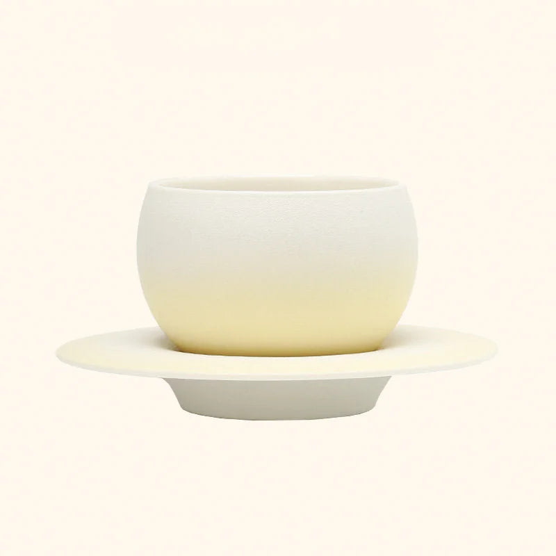 The Lemon Yellow Ombre Ceramic Cup displayed on its matching Saturn-ring saucer. - RoomDen