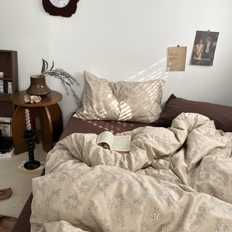 Beige botanical cotton bedding set with small pink flowers and green leaves, styled on a bed - Roomden