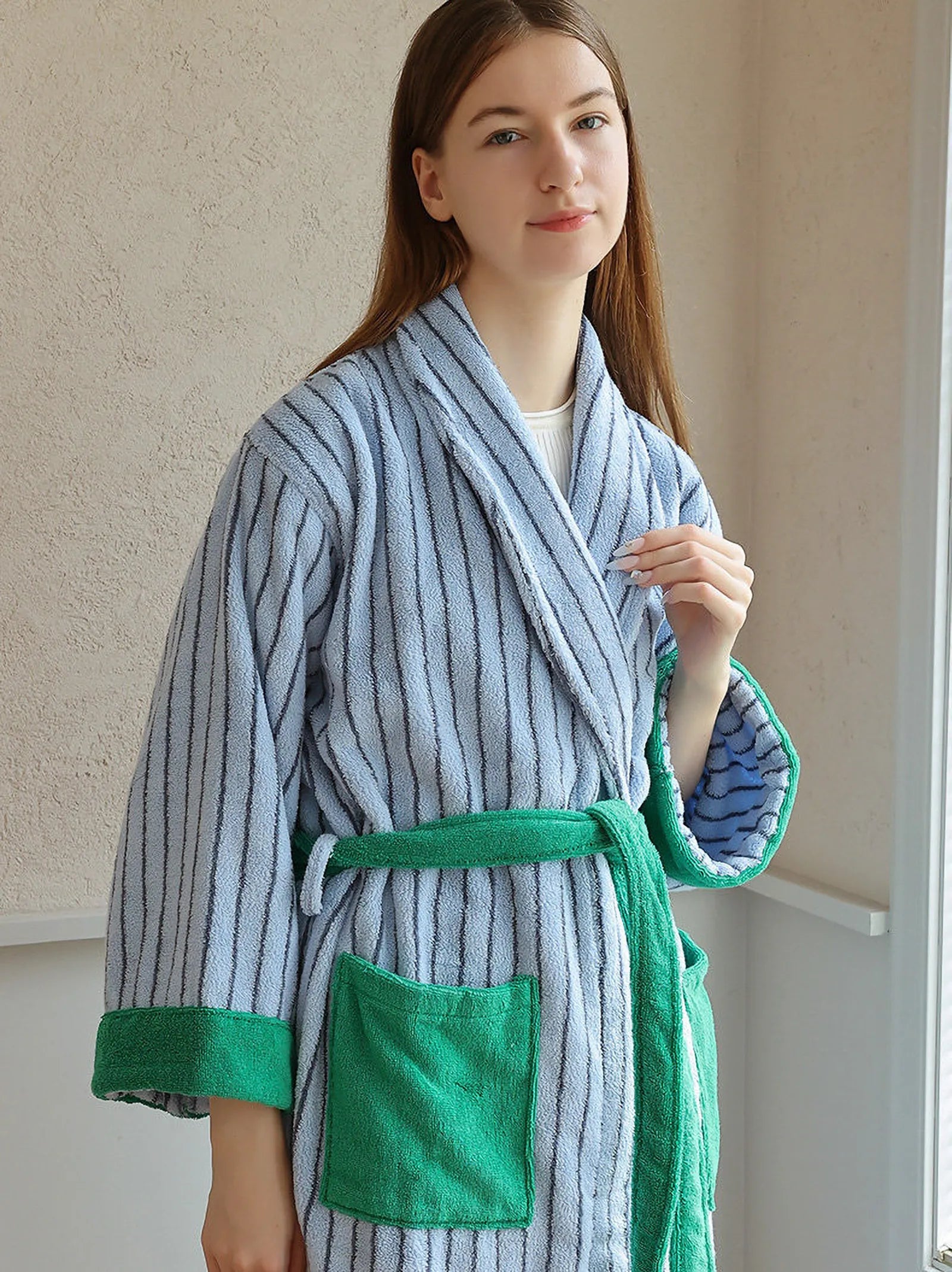 Front view of a woman standing in a blue striped cotton robe with green waist tie.