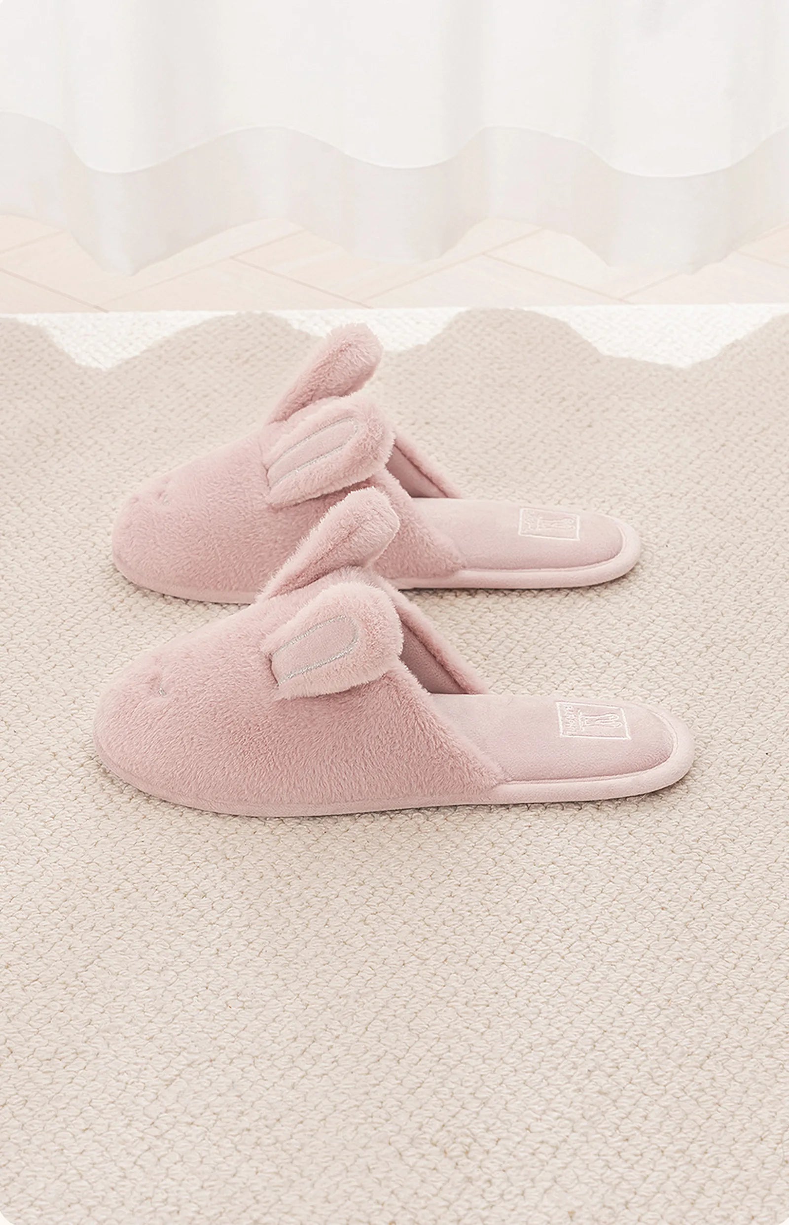 Pink embroidered bunny house slippers on beige textured rug - RoomDen