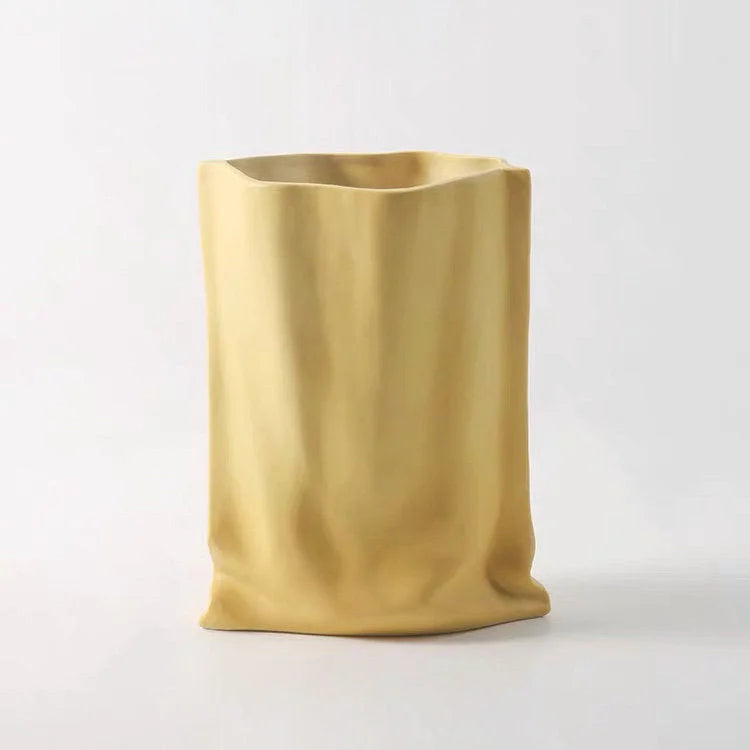 The Frosted Ruched Ceramic Paper Bag Vase shown in a warm Mustard Yellow color - RoomDen.