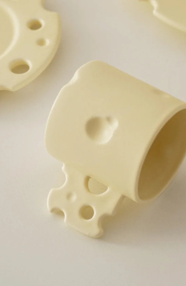 Detailed view of the cheese-hole handle on the yellow ceramic mug. - RoomDen