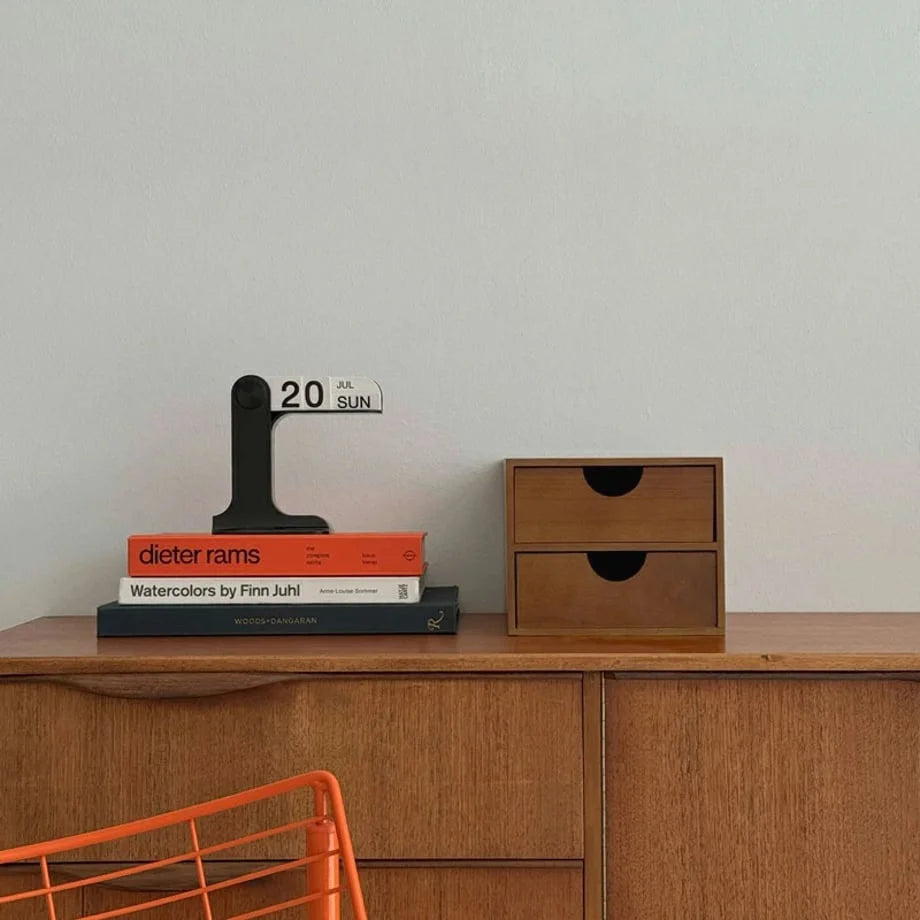 The wooden desktop organizer sitting on a vintage credenza next to a flip calendar and a stack of art books. - RoomDen