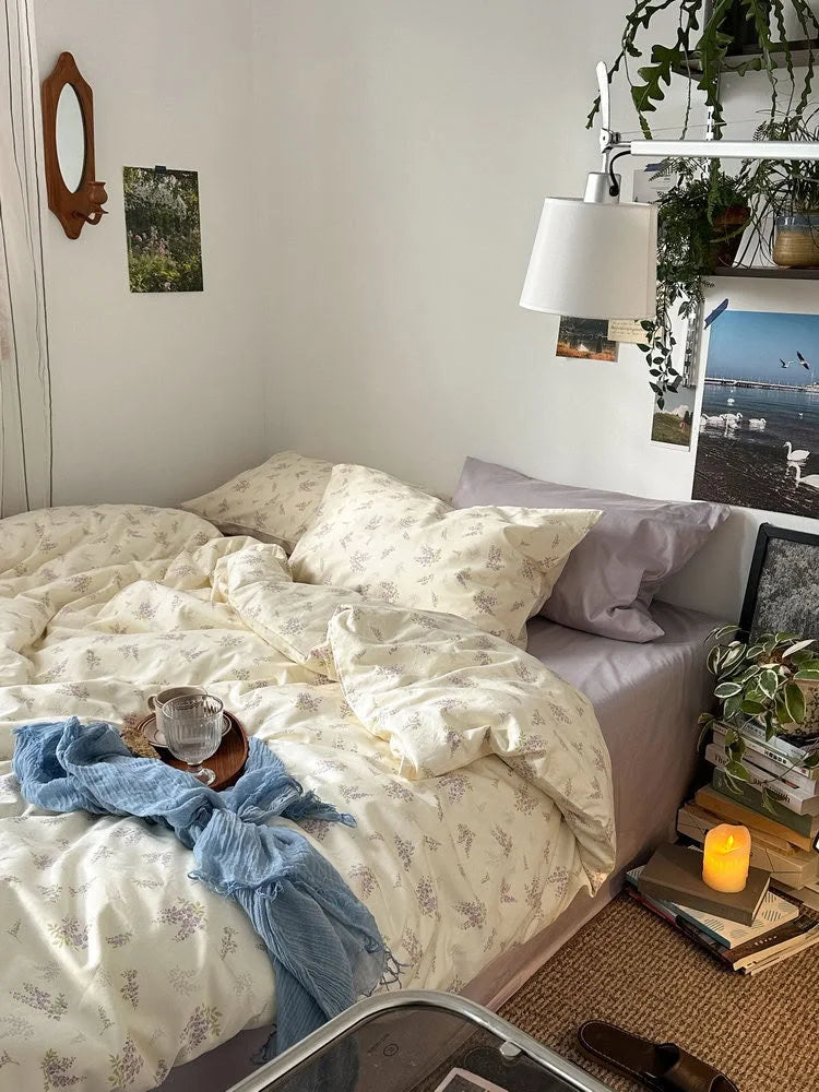 Angled view of the lavender floral bedding set, showing the soft texture and room decor with a wall mirror and lamp - RoomDen.