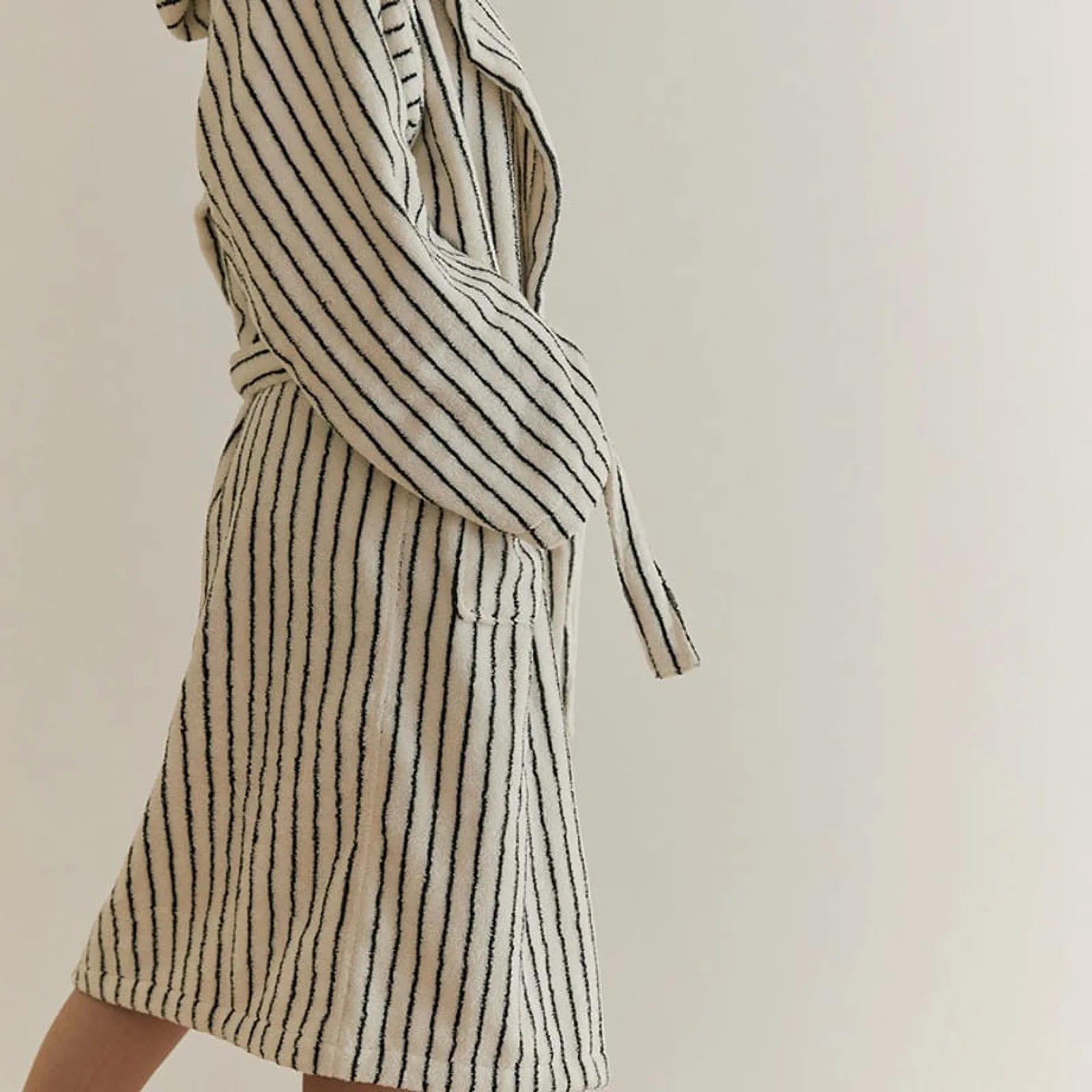 Side standing view showing the length and relaxed fit of the cream striped cotton bathrobe.