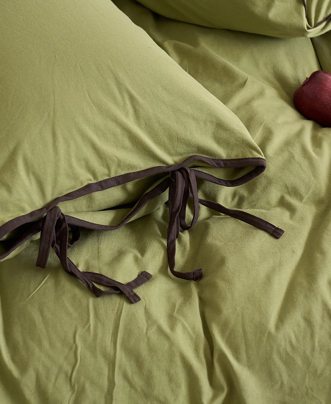 Detail of the Matcha Green & Brown washed cotton bedding, focusing on the brown tie closure. - RoomDen