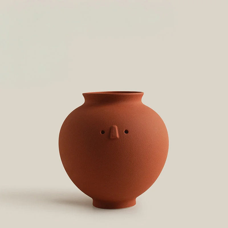 A studio shot of the terracotta Pot Frosted Minimalist Face Vase against a light beige background. - RoomDen