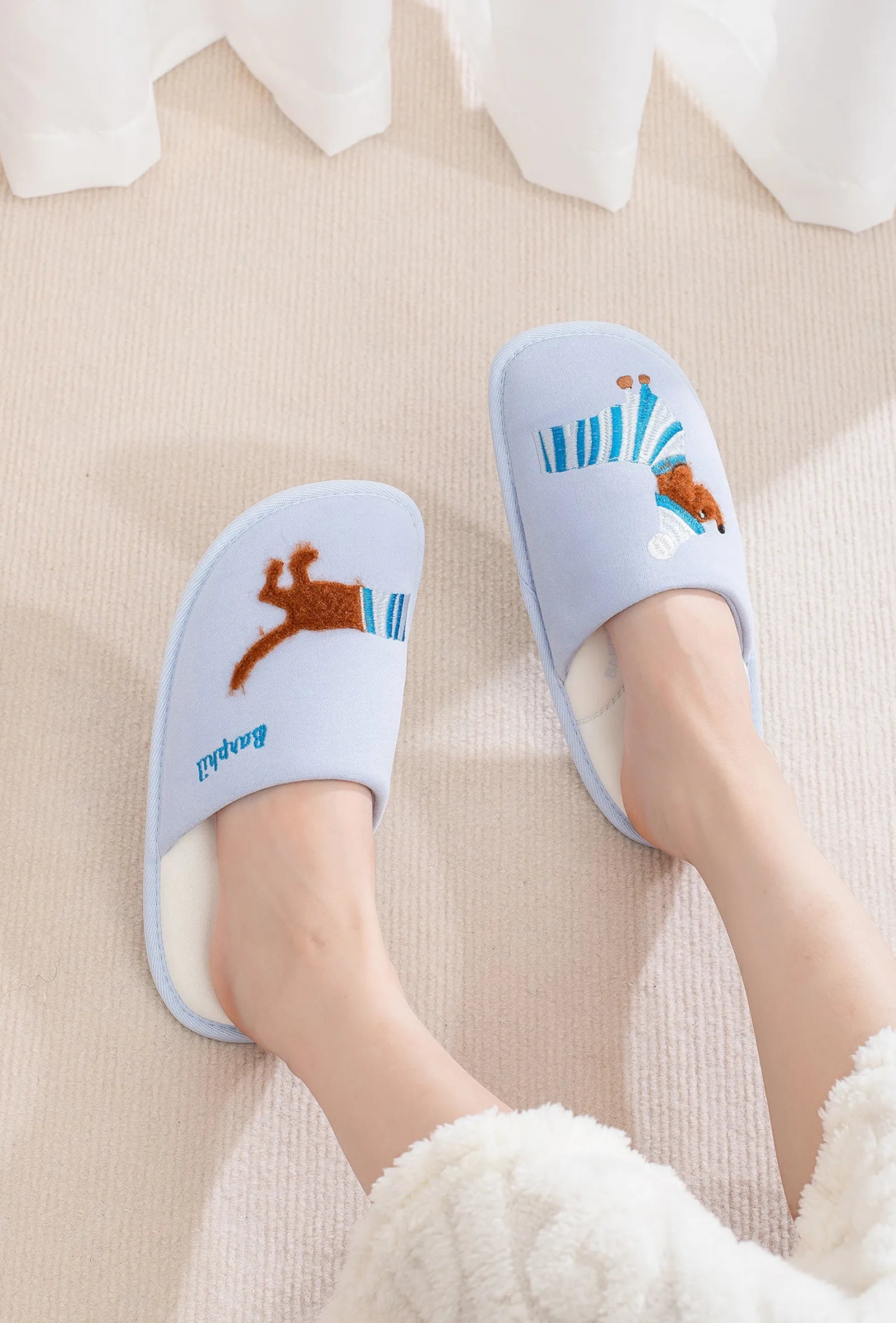 Baby blue open-toe slides with sausage dog embroidery worn on feet top down view