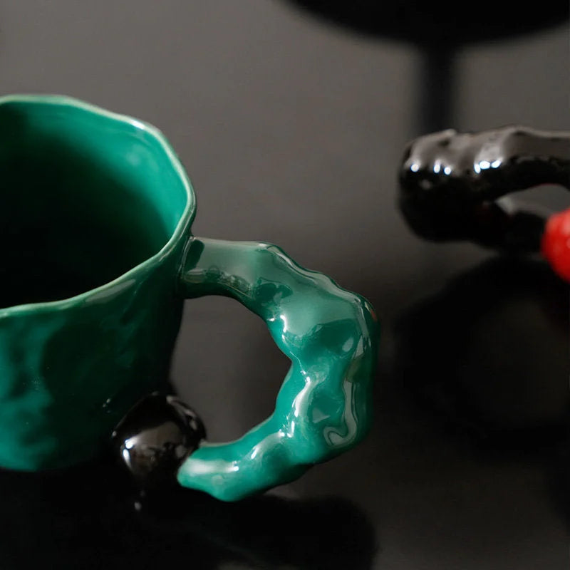 Close-up of the emerald green sculptural ceramic mug's chunky handle and textured surface - RoomDen.