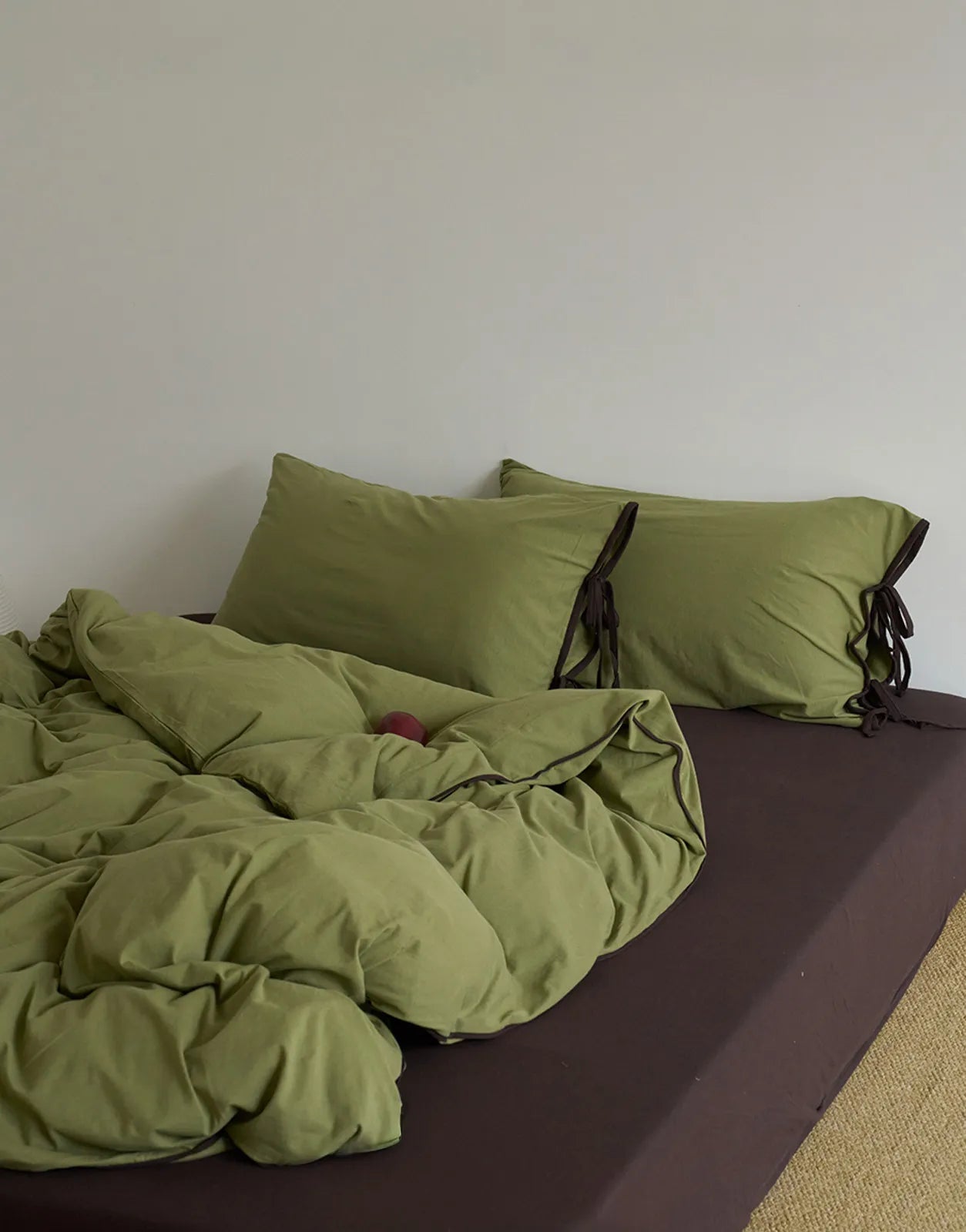 Matcha Green & Brown bedding set on a bed against a white wall, creating a natural, earthy look. - RoomDen