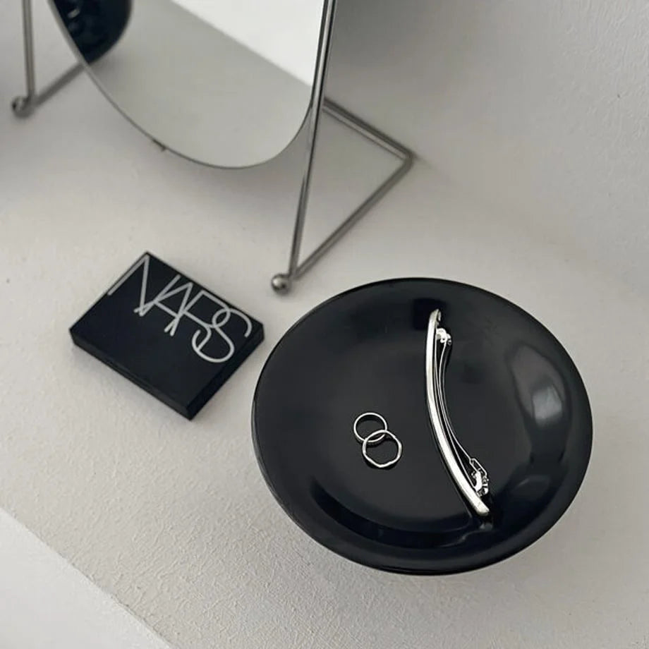 Top-down view of the black jewelry dish, highlighting the silver jewelry against the dark surface. - RoomDen