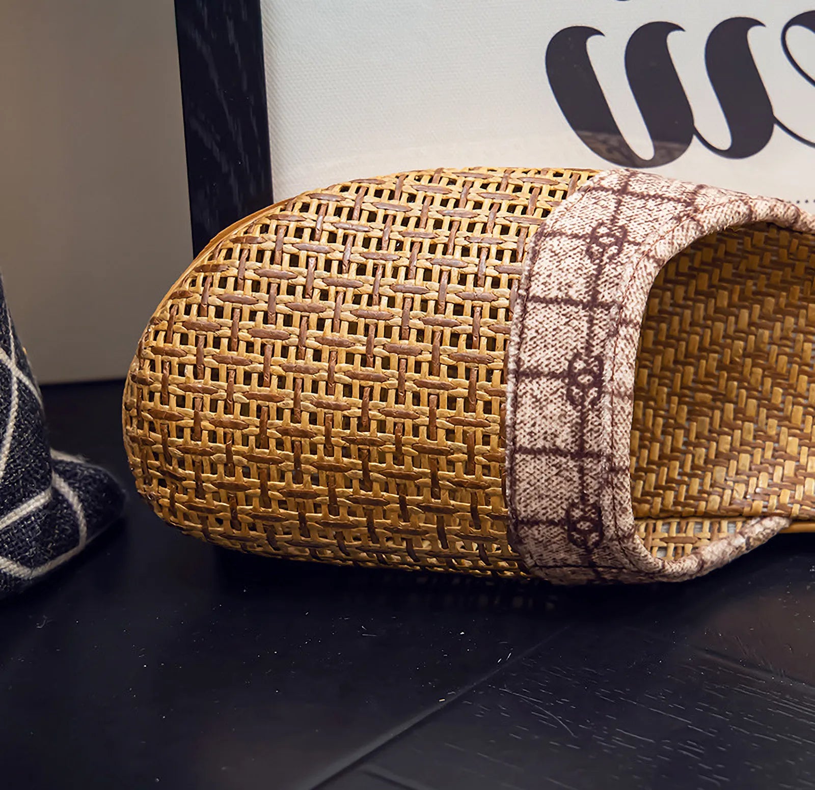 Close-up detail of woven rattan texture and plaid fabric strap on house slippers - RoomDen
