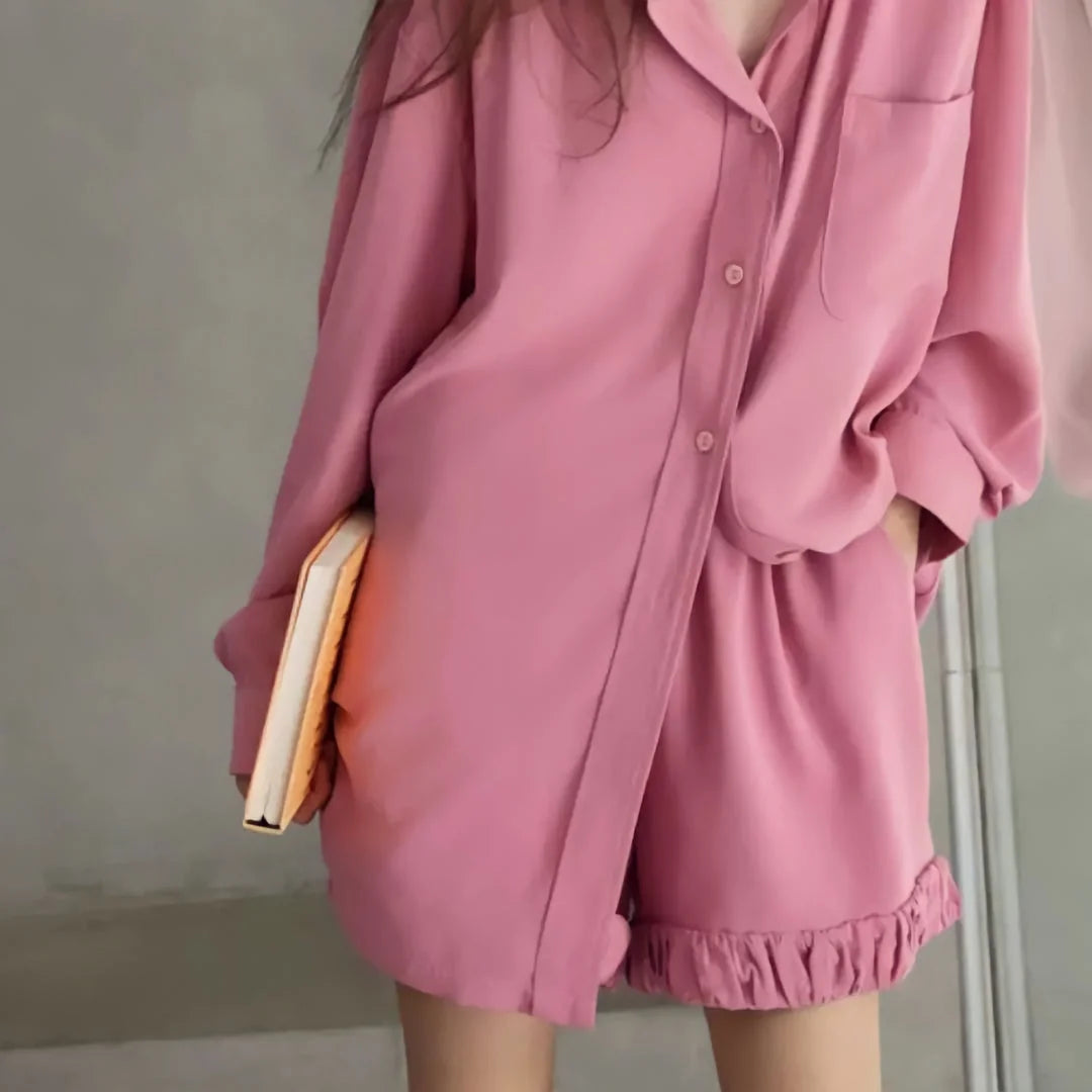 A close-up shot of the torso, detailing the button-down front and ruffle hem of the pink cotton pajamas. - RoomDen