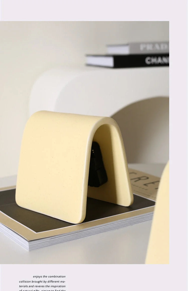 Side profile detail of the Butter Yellow Matte Arch Ceramic Table Clock on a book - RoomDen