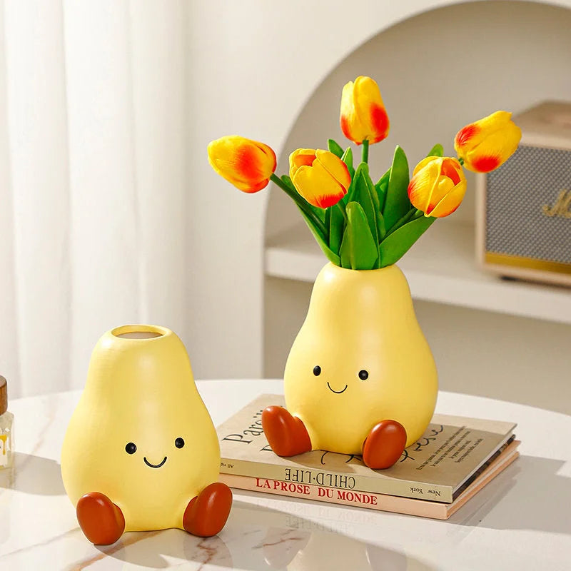 An empty Cheerful Smiley Face Ceramic Pear Vase next to one holding yellow tulips, showcasing its shape and finish on a desk - RoomDen.