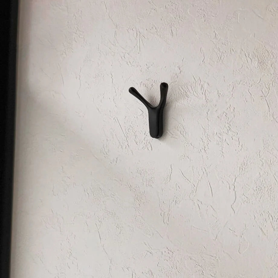 Variant Close-up: A single black branch-shaped metal hook on a textured white wall - RoomDen