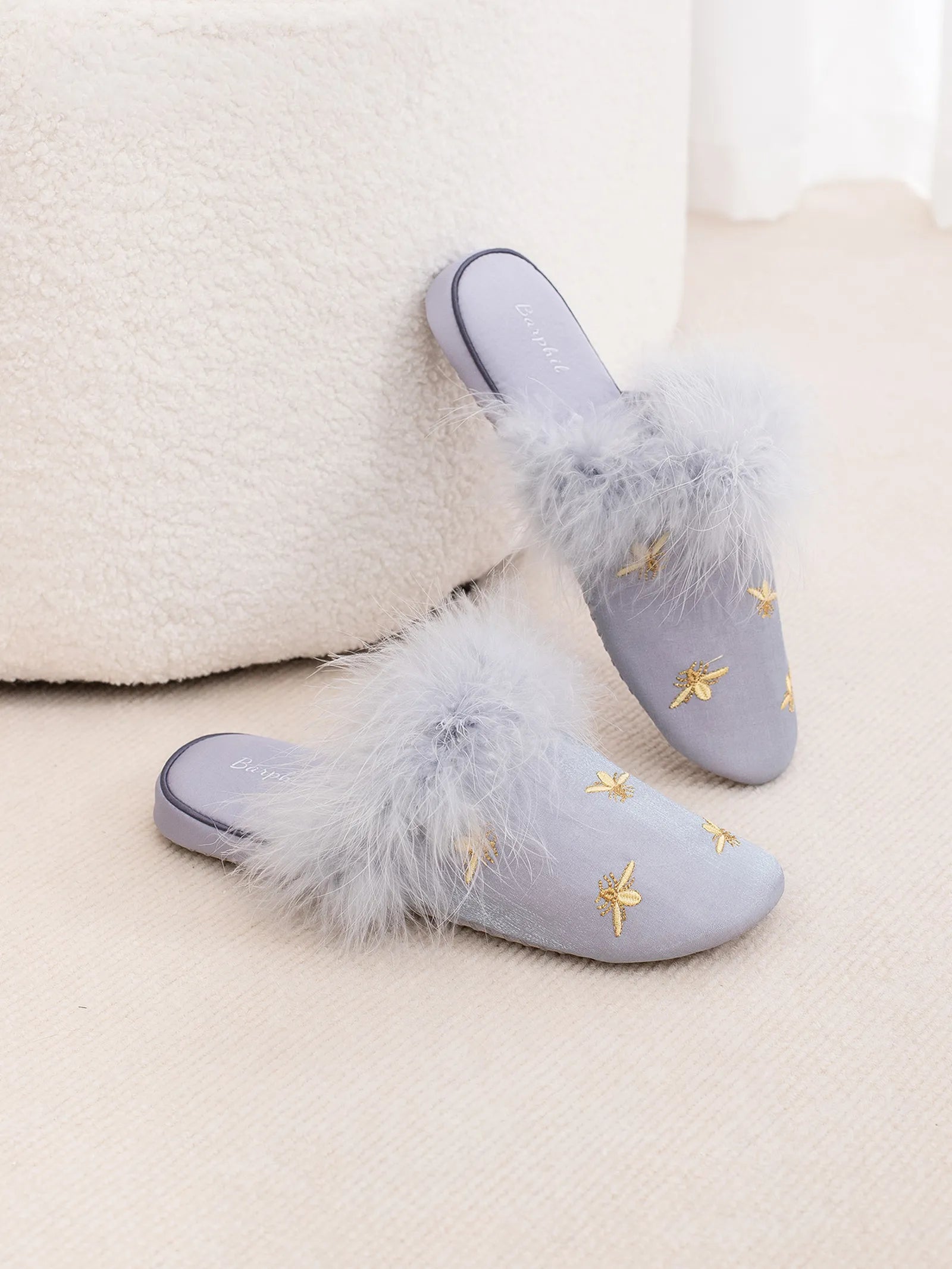Blue fluffy slippers leaning on a white prop showing gold embroidery - RoomDen