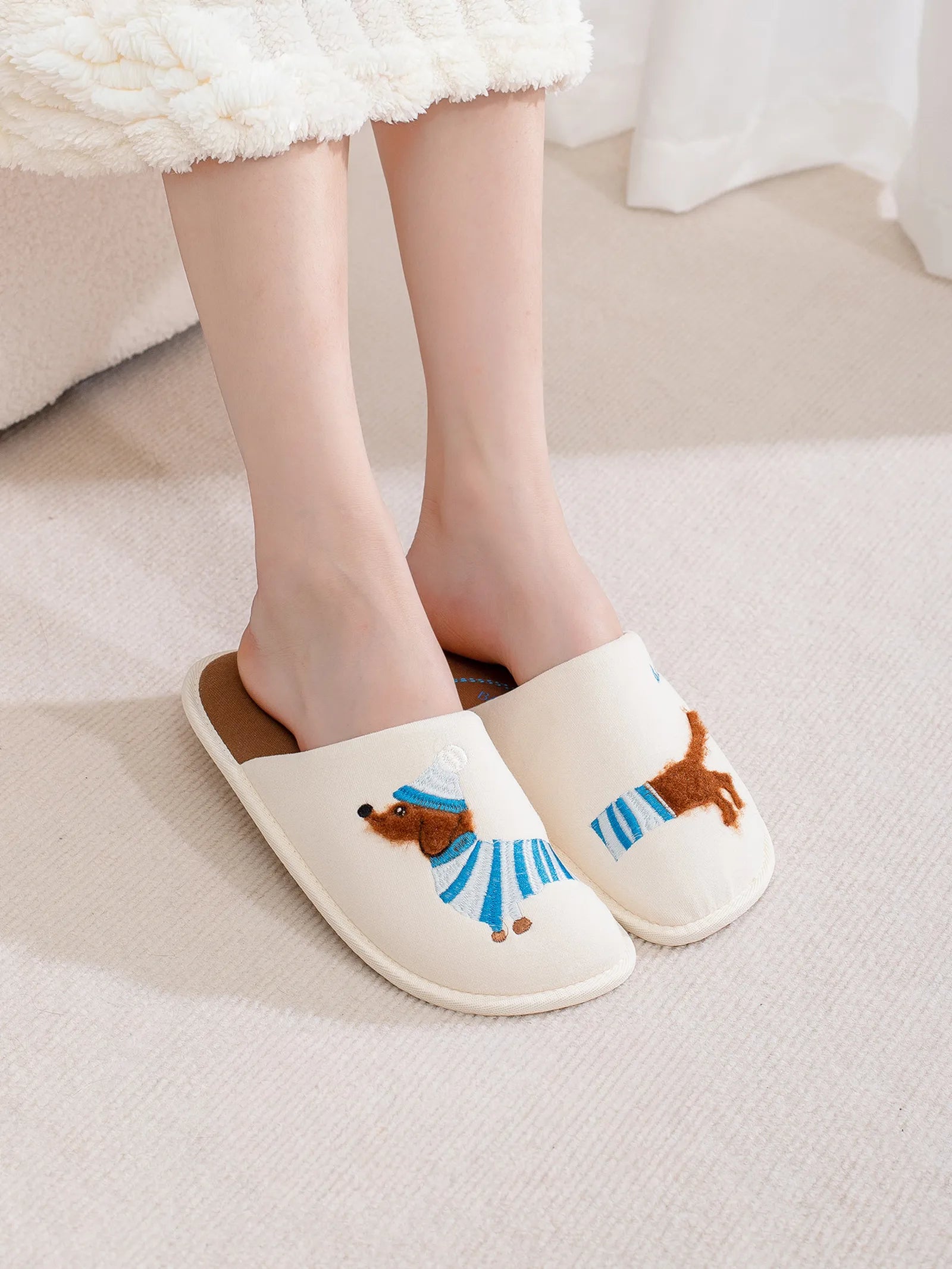 Woman wearing white dachshund slippers standing on beige carpet showing fit