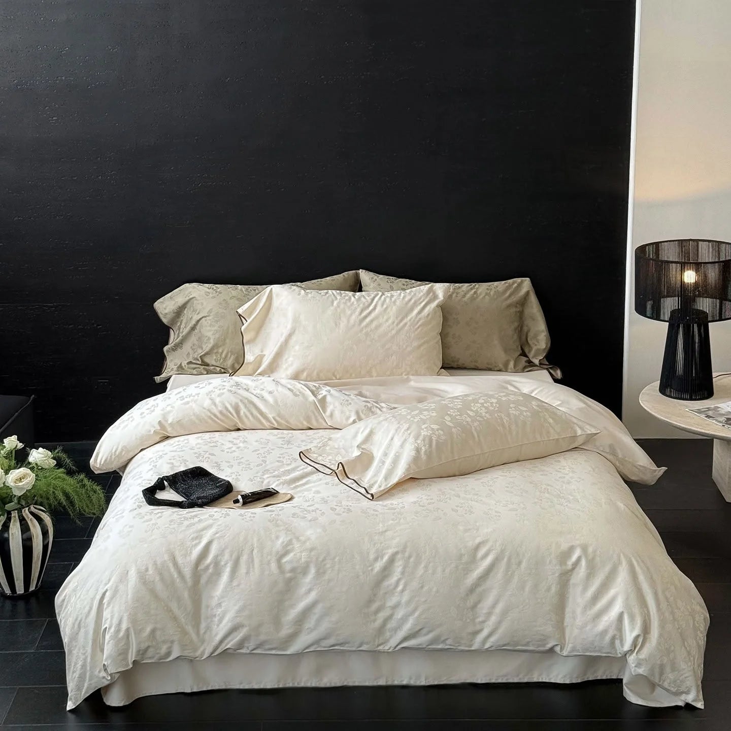 Full view of the Pearl White silky floral jacquard cooling Tencel bedding set on a bed against a black wall, showing an elegant, minimalist bedroom. - RoomDen