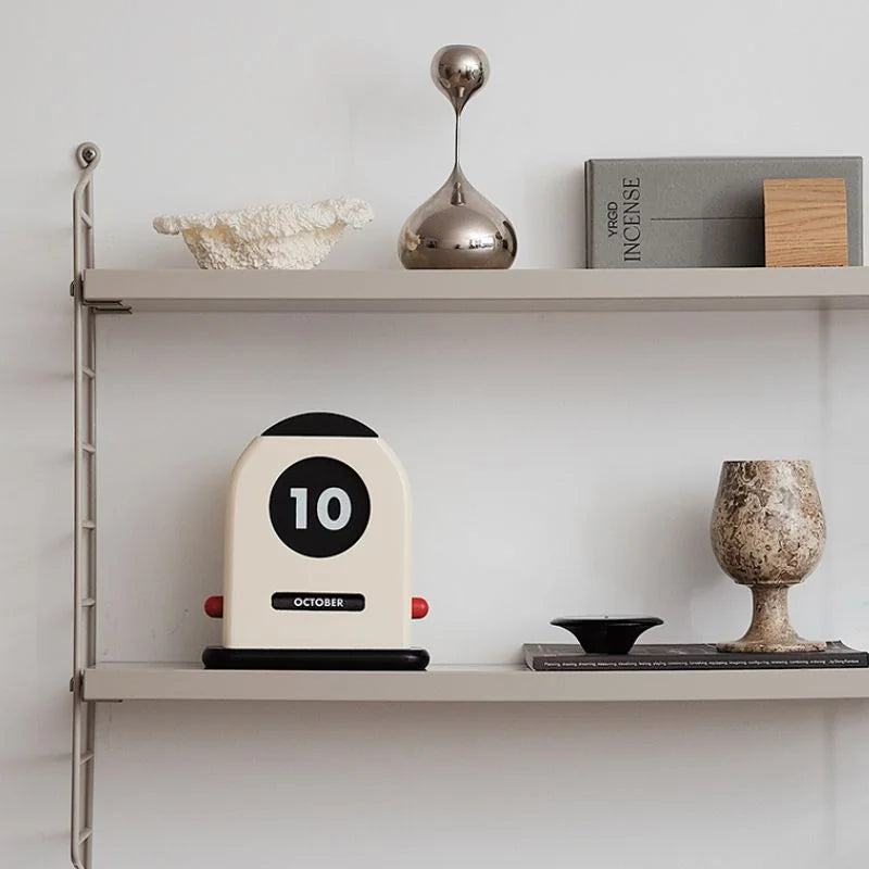 The perpetual calendar styled on a grey metal wall shelf with other Japandi decor pieces - RoomDen