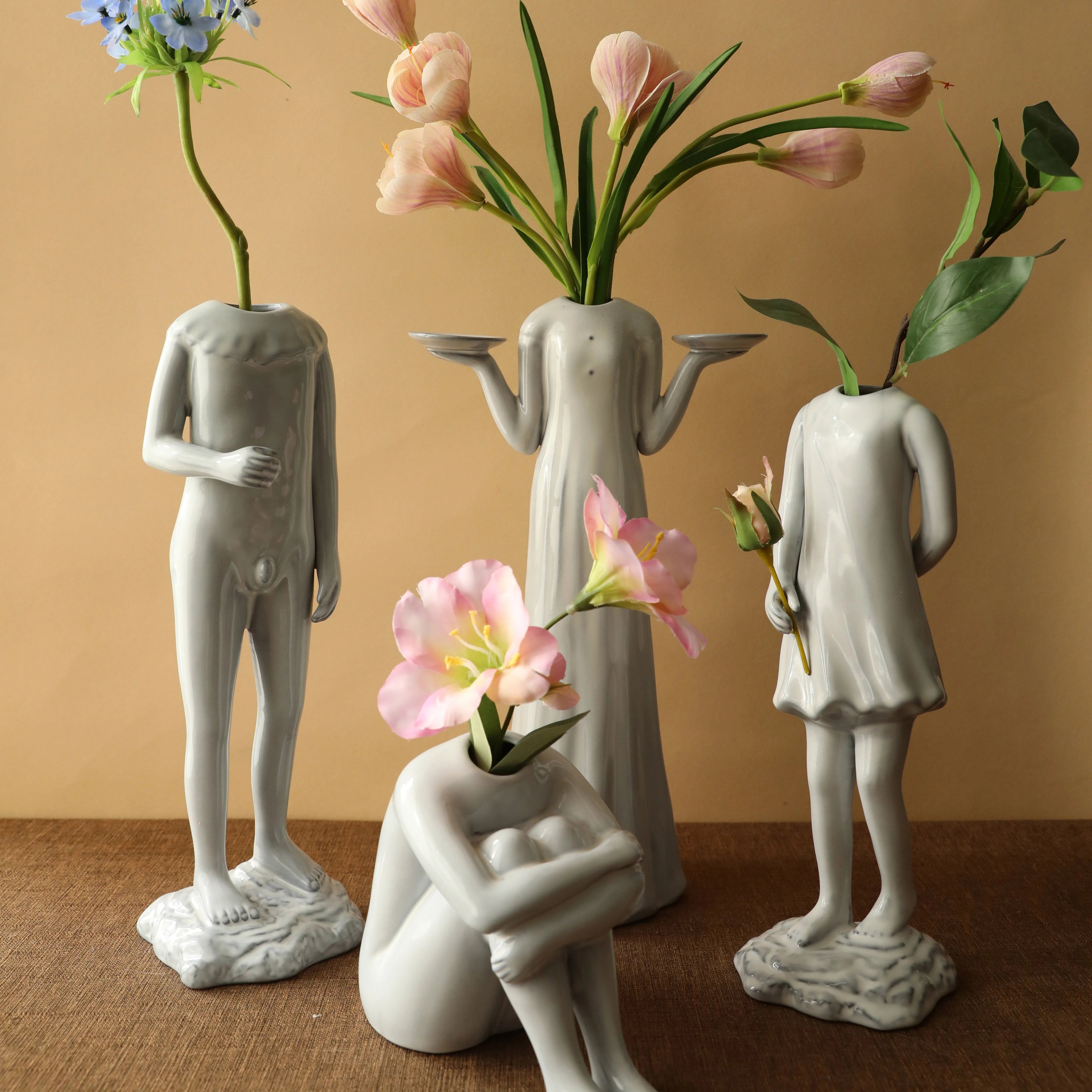 Lifestyle shot of the four sculptural body form vases, each holding different colored flowers. - RoomDen