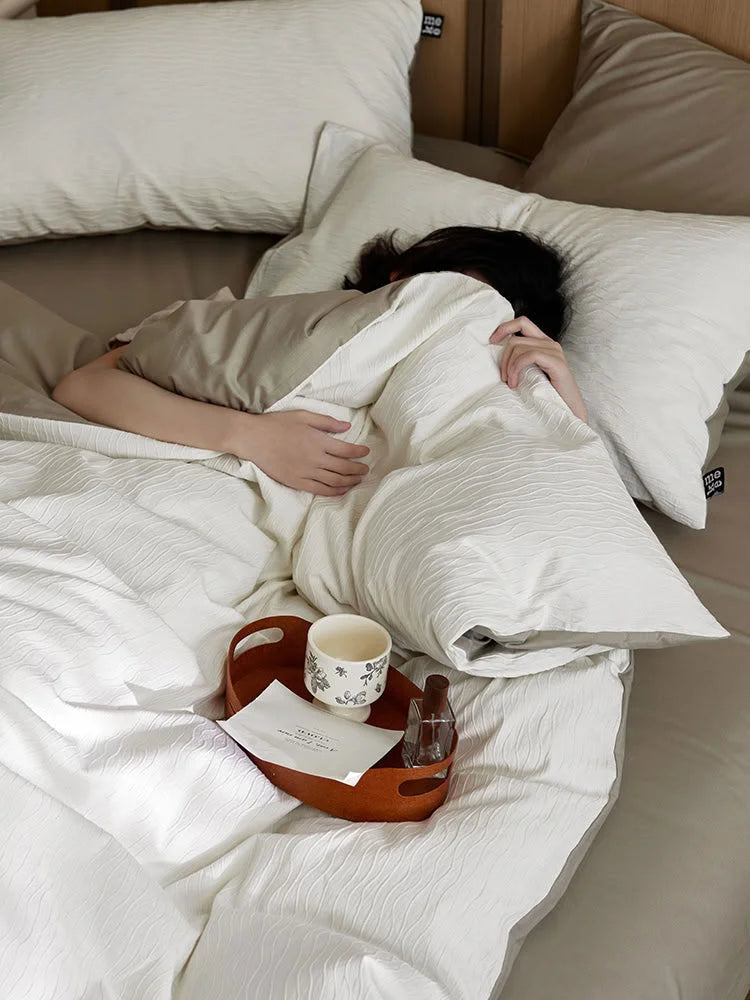A person nestled under the Cream White Wavy Textured duvet cover, highlighting its coziness. - RoomDen