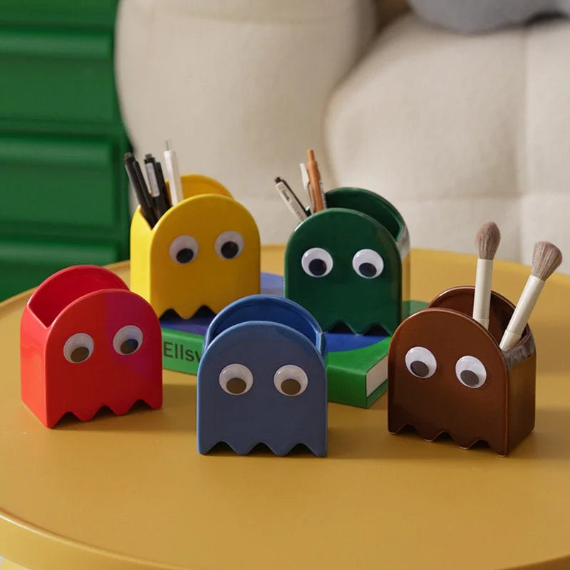 A collection of five Retro Ghost Ceramic Pen Holders in red, blue, yellow, green, and brown on a desk - RoomDen.