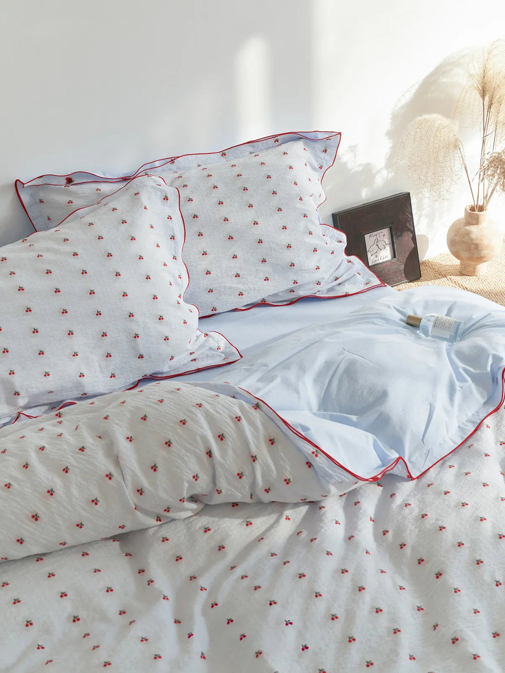 Ruffled Cherry Print Washed Cotton Bedding Set on a bed with soft natural light. - RoomDen