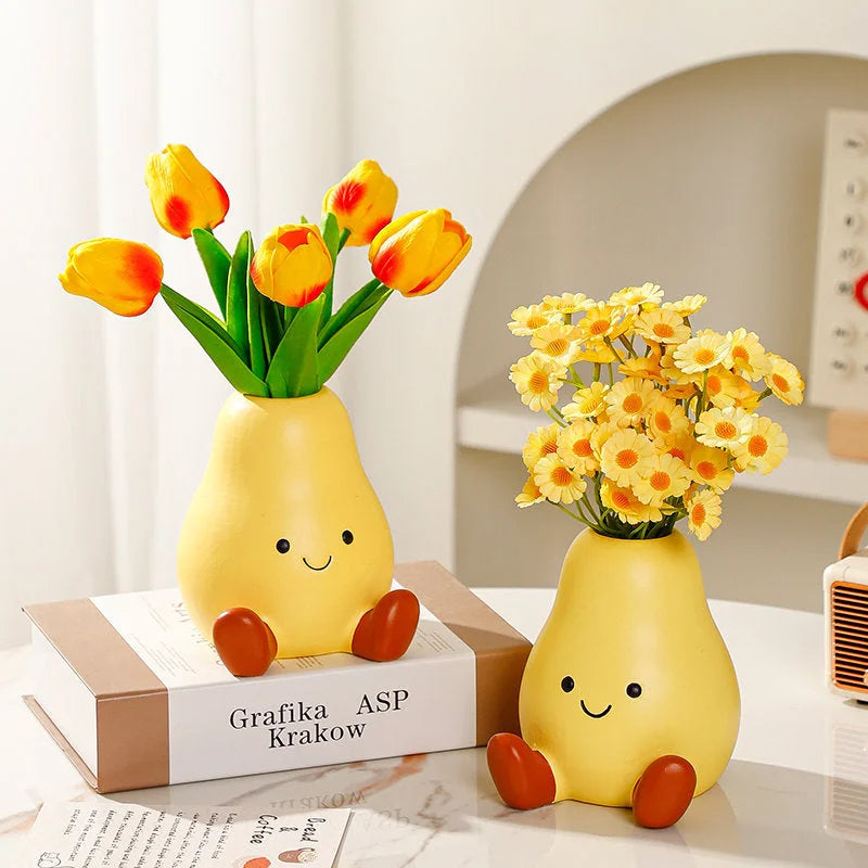 Two Cheerful Smiley Face Ceramic Pear Vases on a desk, one holding yellow tulips and the other yellow daisies - RoomDen.