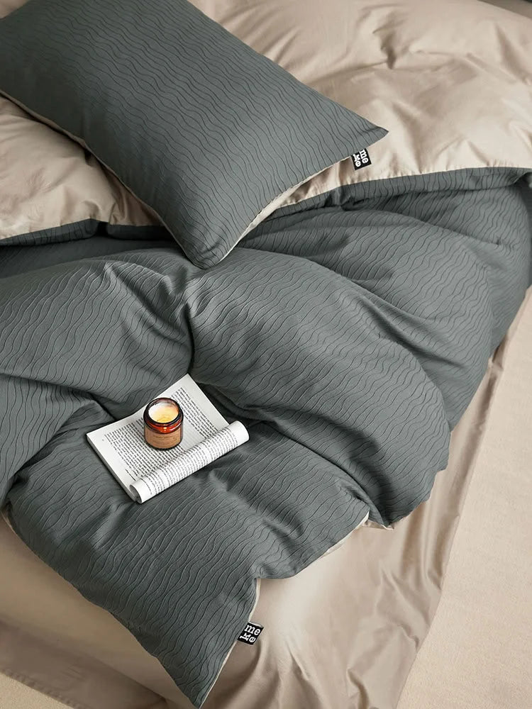 Top-down detail shot of the wavy texture on the Slate Grey duvet cover with a candle and book. - RoomDen