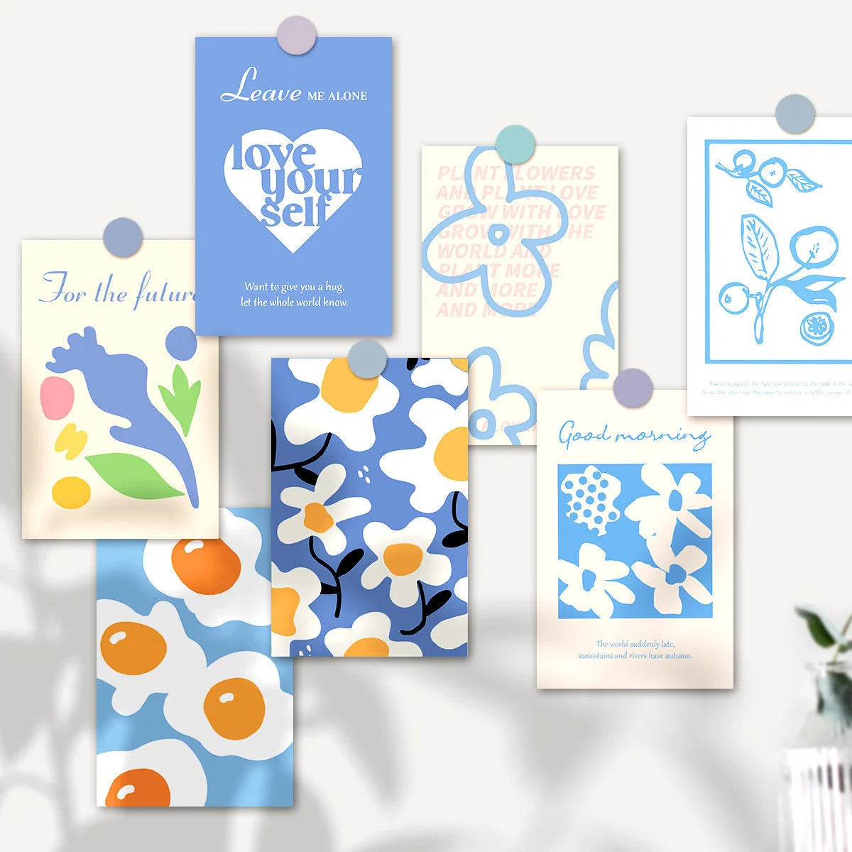 A selection of blue, yellow, and white themed cards from the wall collage kit arranged on a wall, featuring daisy and fried egg patterns. - RoomDen