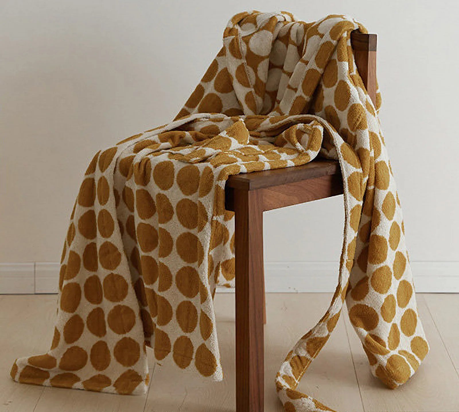 Mustard yellow polka dot hooded bathrobe draped over a wooden chair - RoomDen