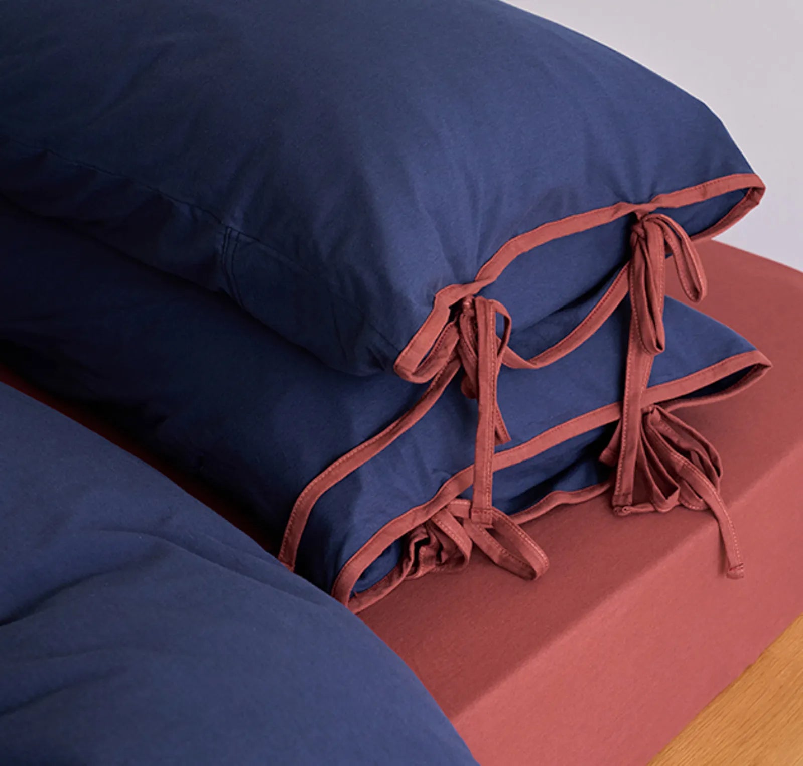 Close-up of the terracotta tie closures on the navy blue washed cotton pillowcases. - RoomDen