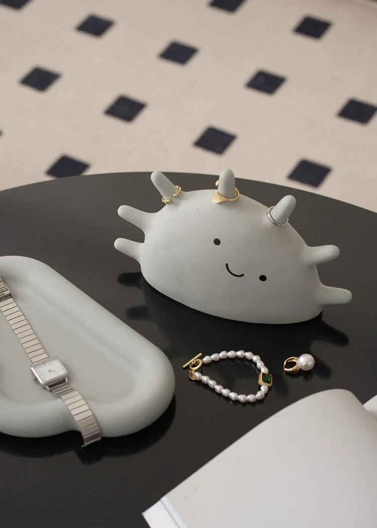 Light Grey Smiling Sun Jewelry Organizer on a black coffee table with a watch and bracelet nearby - RoomDen