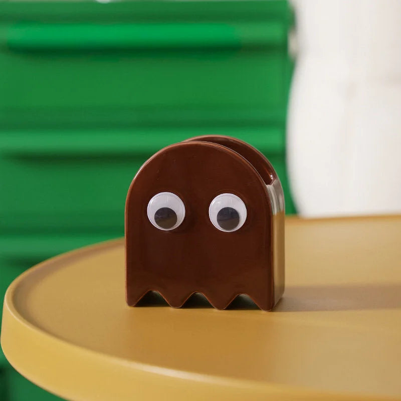 The brown Retro Ghost Ceramic Pen Holder on a yellow table with a green background - RoomDen.