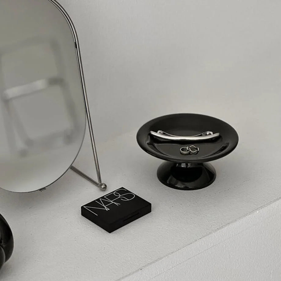 Close-up of the black pedestal jewelry dish holding a silver hair clip and rings, variant image. - RoomDen