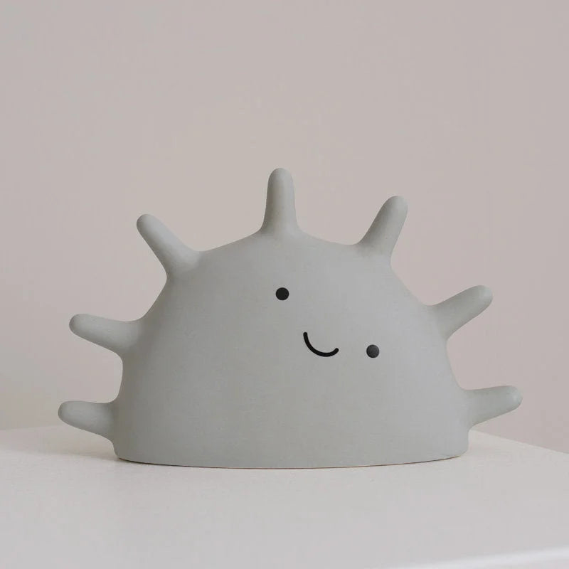 Front view of the Light Grey Matte Ceramic Smiling Sun Jewelry Organizer on a white surface - RoomDen