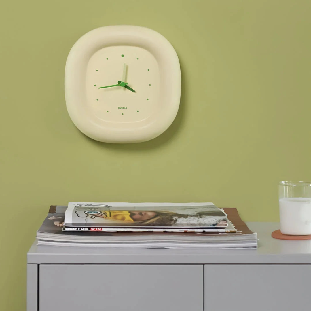 The Creamy Beige Puffy Bubble Table Clock mounted on a sage green wall above a grey console table - RoomDen
