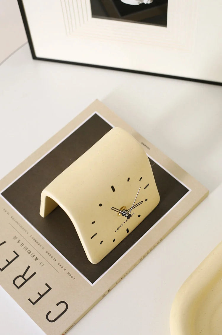 Top-down view of the Butter Yellow Matte Arch Ceramic Table Clock on a magazine - RoomDen