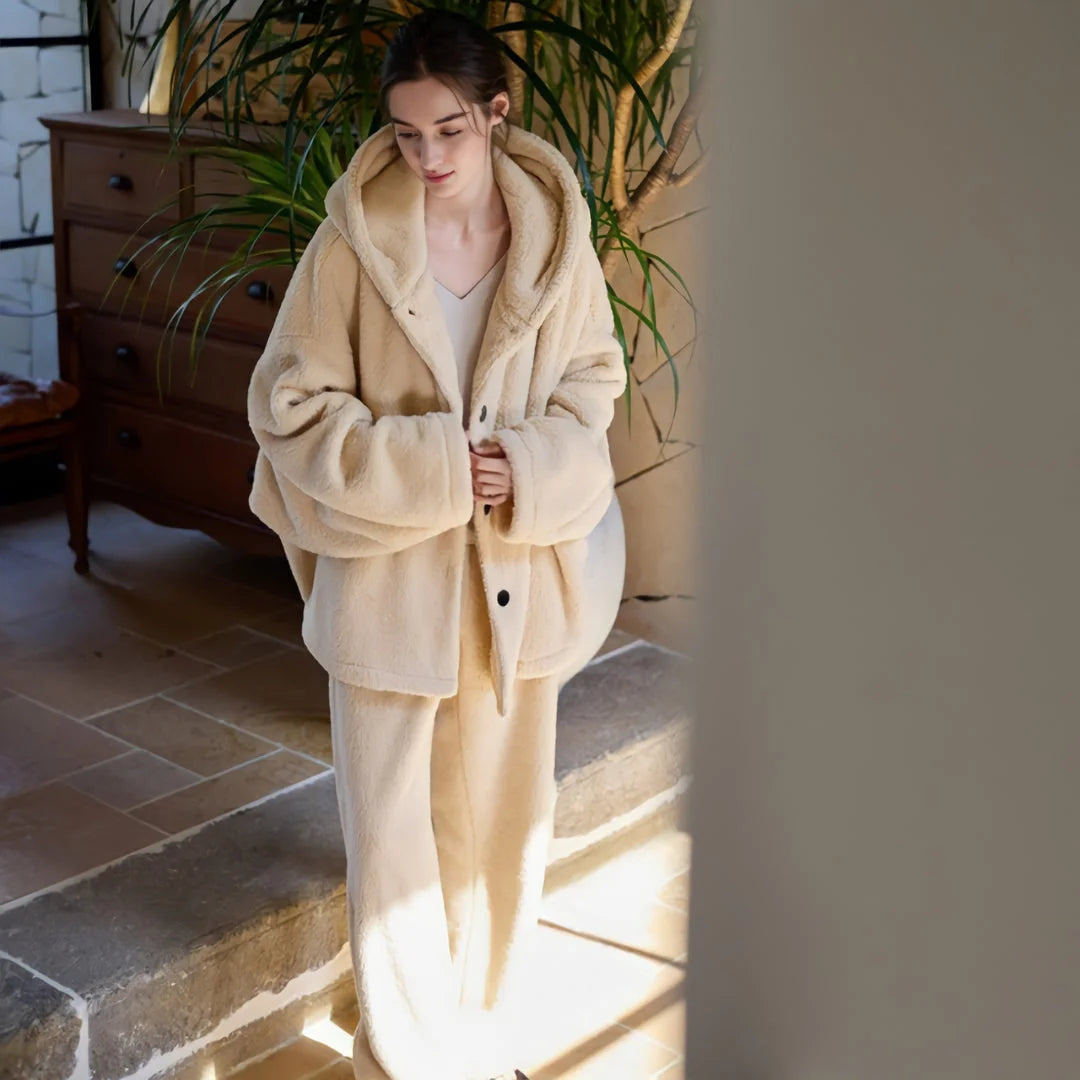 Model in a creamy beige plush hooded pajama set standing in a sunlit room. - RoomDen
