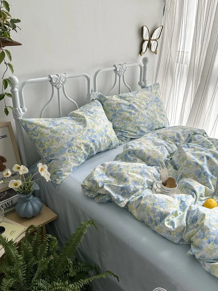 Breezy Watercolor Floral Cotton Bedding Set on a white vintage metal bed, styled with plants and a cup of tea. - RoomDen