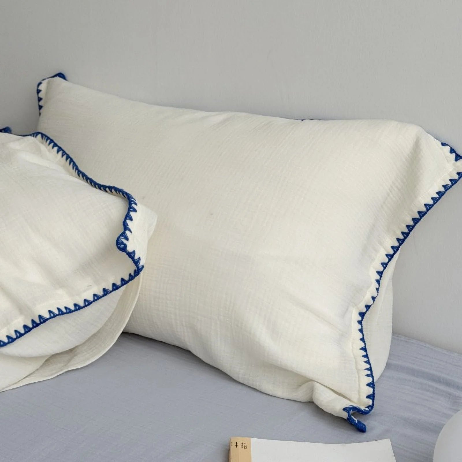 Pillowcases from the cream white and blue embroidered edge bedding set, highlighting the soft texture.