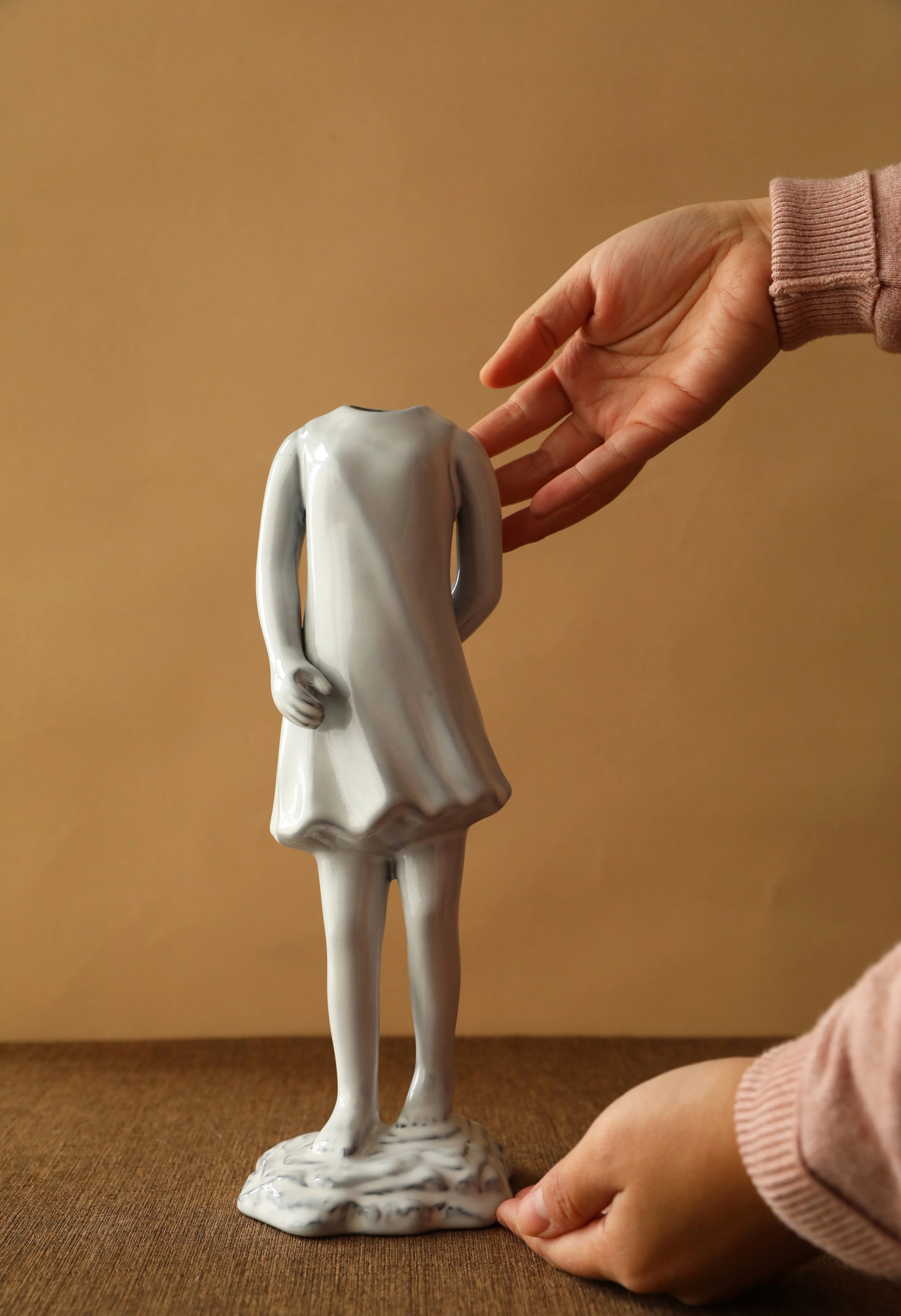 Hand presenting the ceramic vase shaped like a girl in a dress from behind. - RoomDen