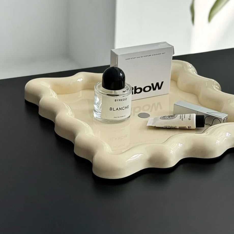 Close-up detail of the glossy finish and sculptural wavy edge of the cream tray - RoomDen