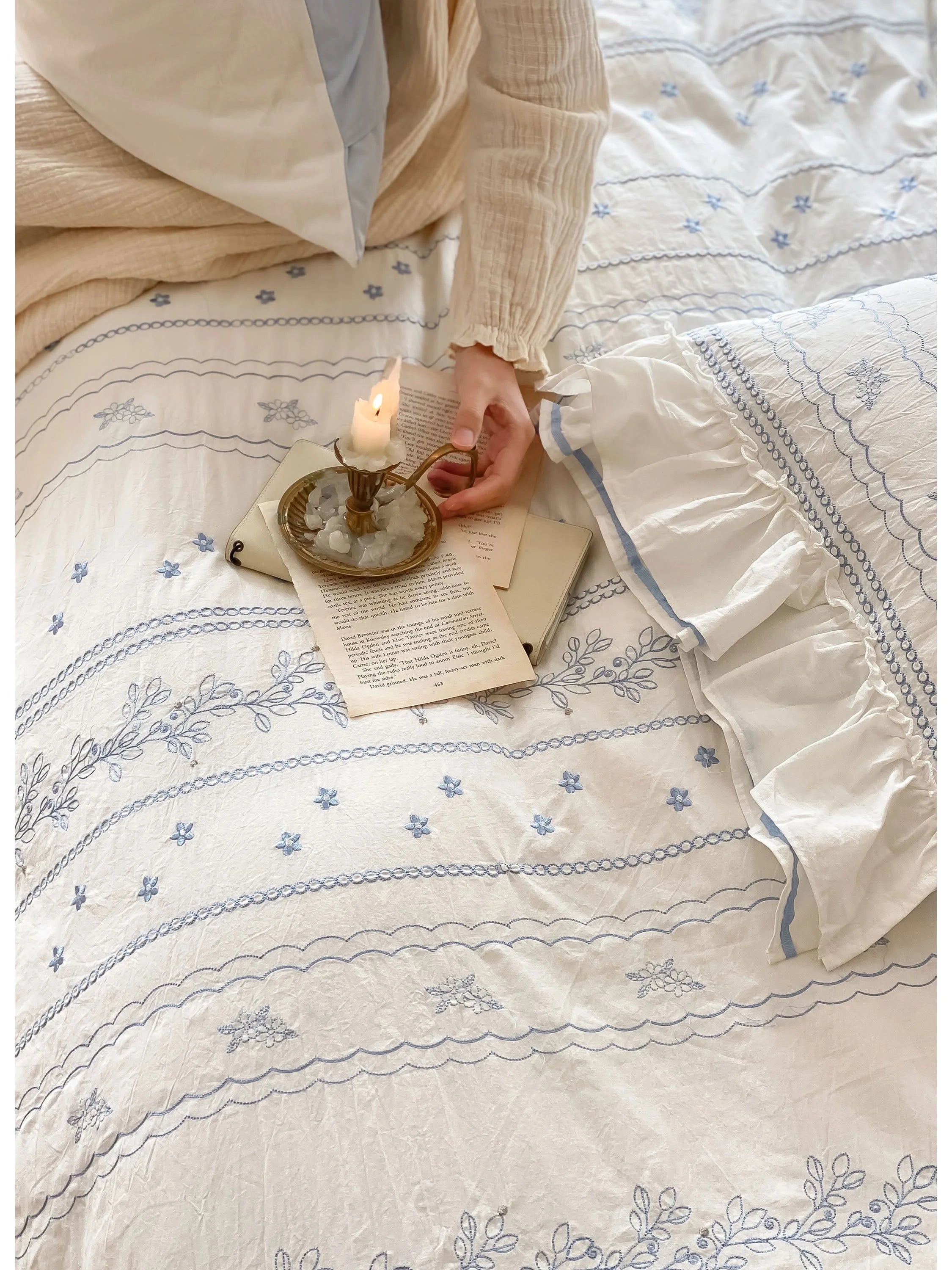 A hand holding a candle over the Ruffled Floral Vine Embroidered Duvet Cover, highlighting the texture.