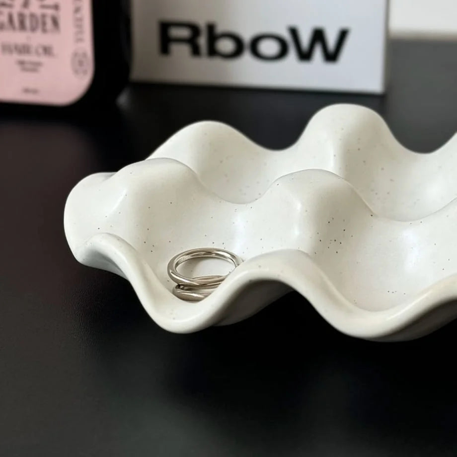 Close-up shot of the textured speckled finish on the white wavy ceramic ring holder. - RoomDen